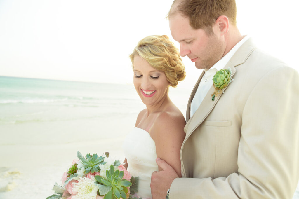 picturesque bride and groom on the beach with pink and green florals